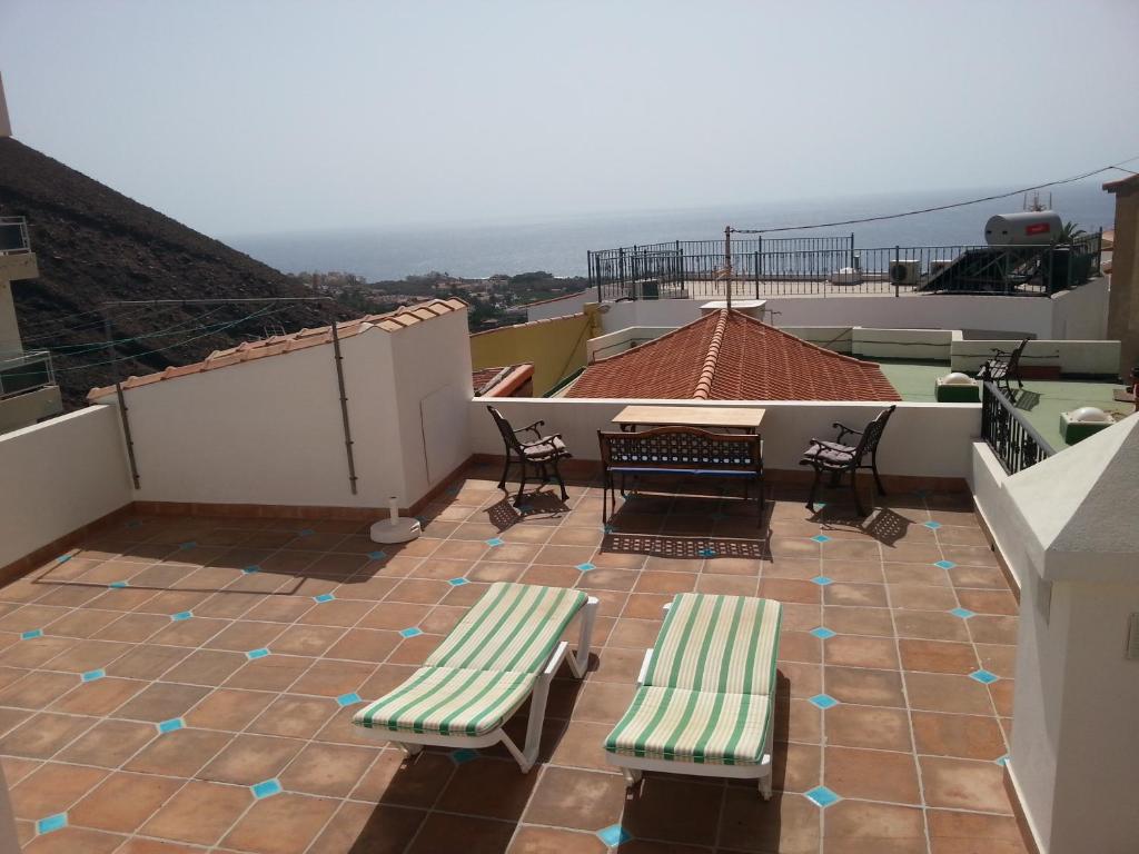 balcón con 2 bancos, mesa y sillas en Casa Emma, en Valle Gran Rey