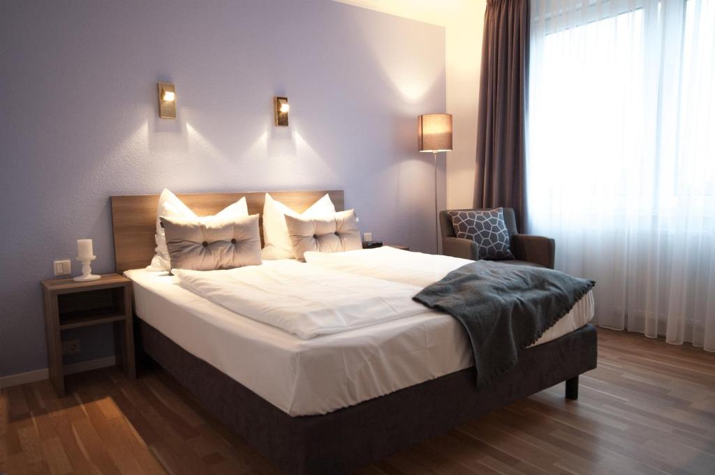 um quarto com uma cama grande e uma cadeira em Kempe Komfort plus Hotel em Solingen