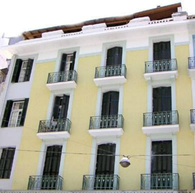 żółto-biały budynek z oknami i balkonami w obiekcie Zeus Hostel w Atenach
