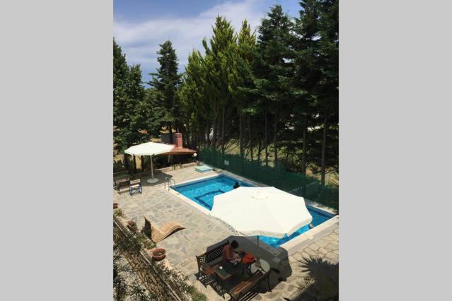 an overhead view of a swimming pool with a table and umbrella at Isabelle's apartment in Kallithea Halkidikis