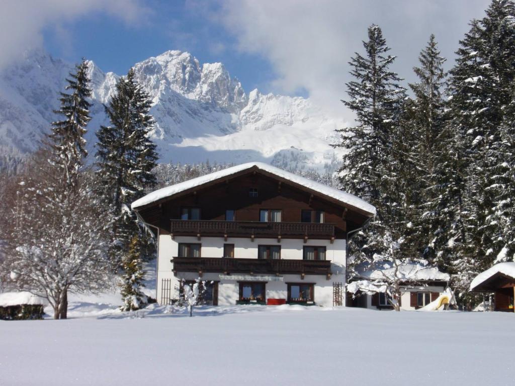 a house in the snow with a mountain in the background at Haus Sonnwend in Ellmau