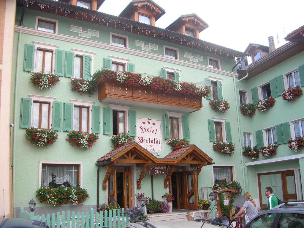 een groot groen gebouw met een bord erop bij Hotel Bertoldi in Lavarone