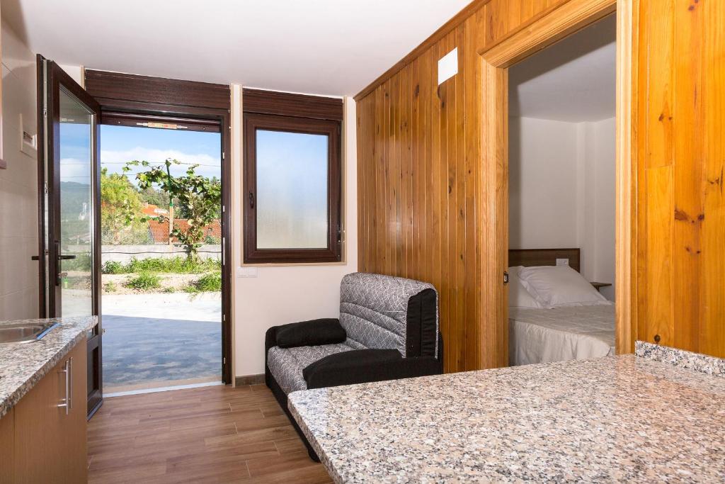a room with a bedroom with a bed and a chair at Viviendas de Uso Turístico in Porto do Son