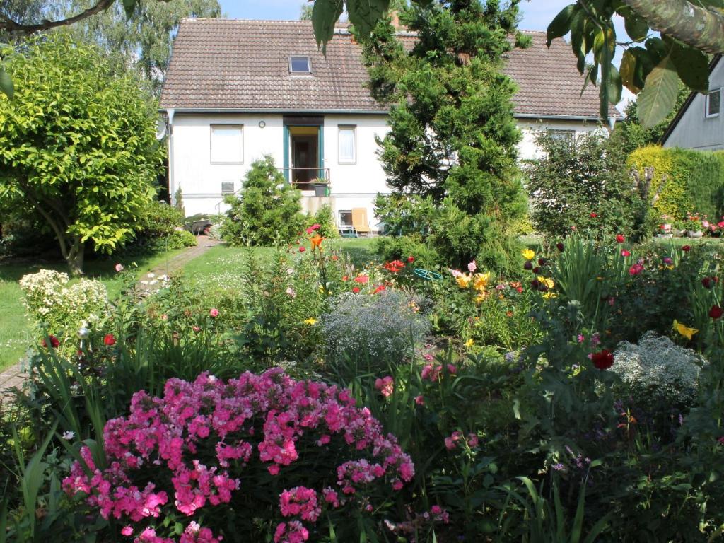 a garden in front of a white house with flowers at Cozy Apartment in Walkendorf with Garden in Walkendorf