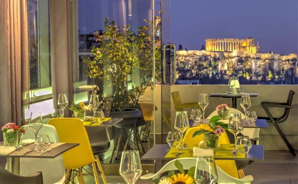 een restaurant met tafels met gele stoelen en bloemen bij Polis Grand Hotel in Athene