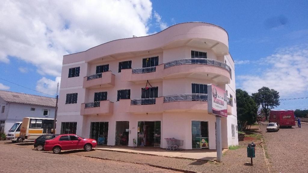 a white building with a car parked in front of it at Apartamento Quadros in Machadinho