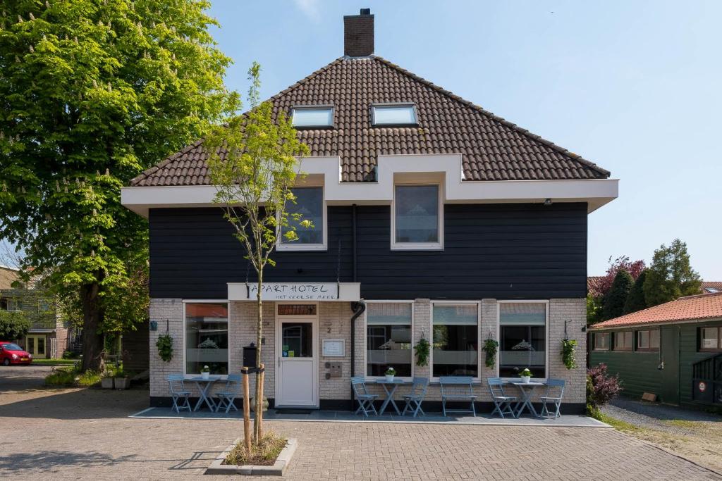 een zwart gebouw met tafels en stoelen ervoor bij Apart Hotel Het Veerse Meer in Kortgene