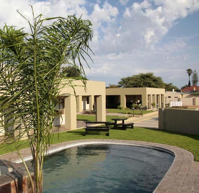 a swimming pool in front of a building with a picnic table at Hadassa Guest House in Otjiwarongo