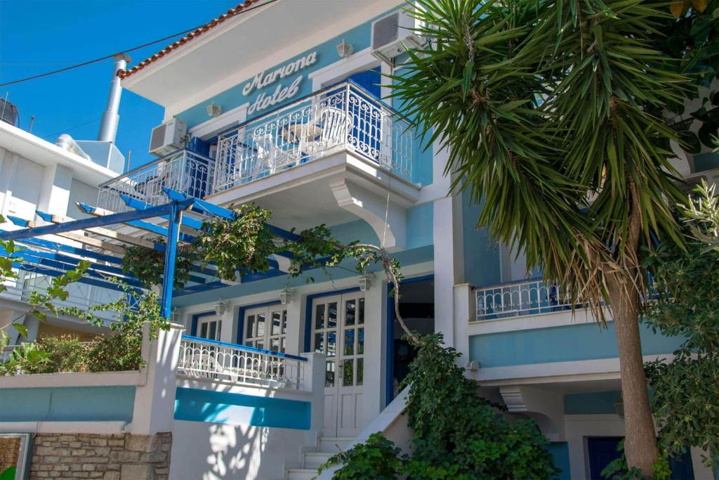 un bâtiment bleu et blanc avec un palmier dans l'établissement Hotel Mariona, à Pythagoreio