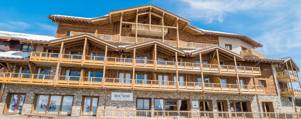 un gran edificio de madera con balcón en Residence Le Roc Noir en La Rosière