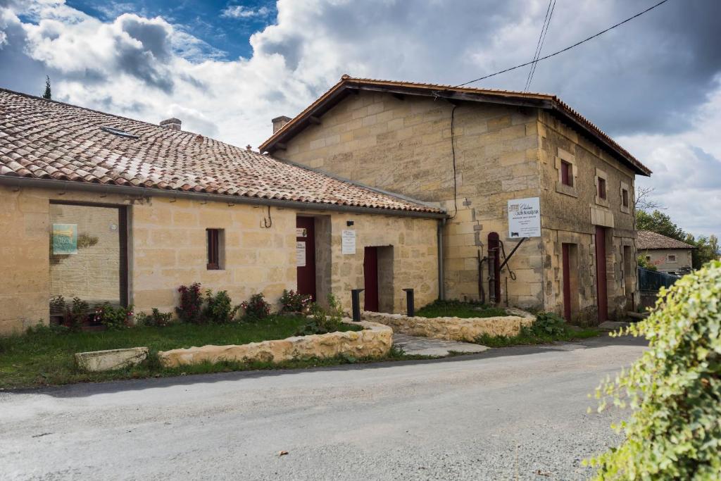 un antiguo edificio de piedra al lado de una carretera en Château Croix Beauséjour "Maison du Vigneron" en Montagne