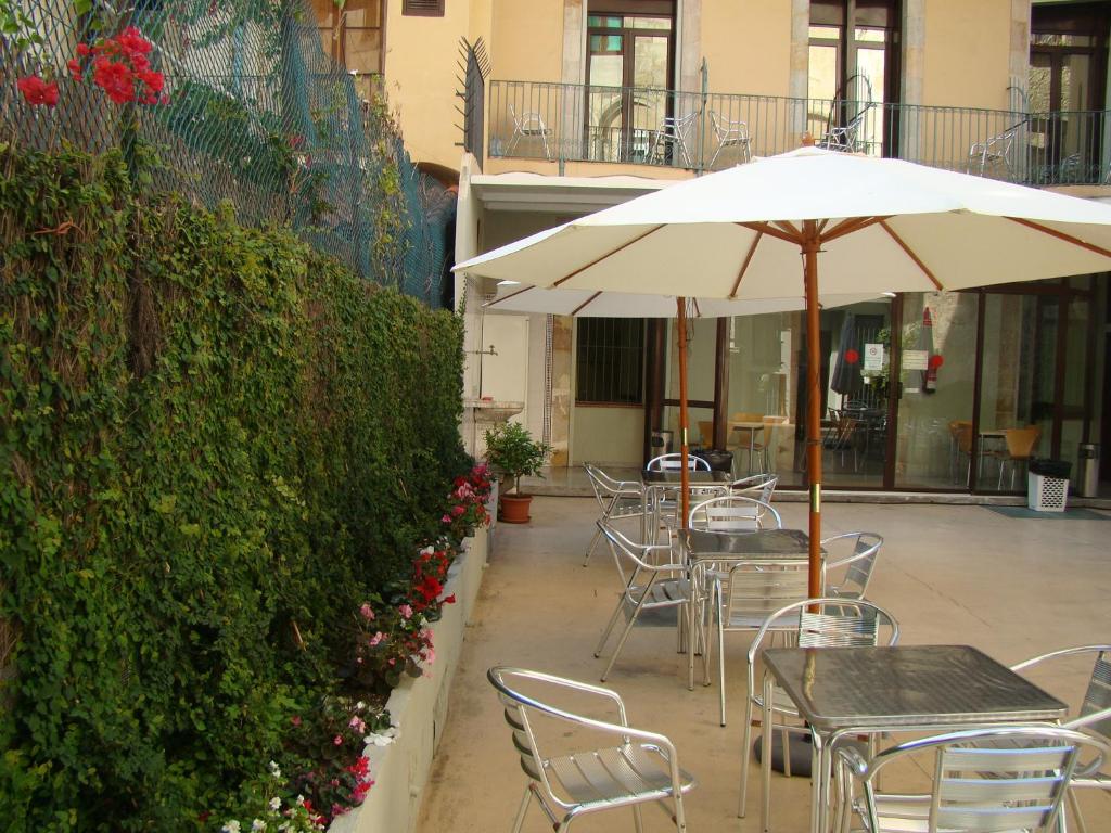 un patio con mesas, sillas y sombrilla en Hostal La Terrassa, en Barcelona
