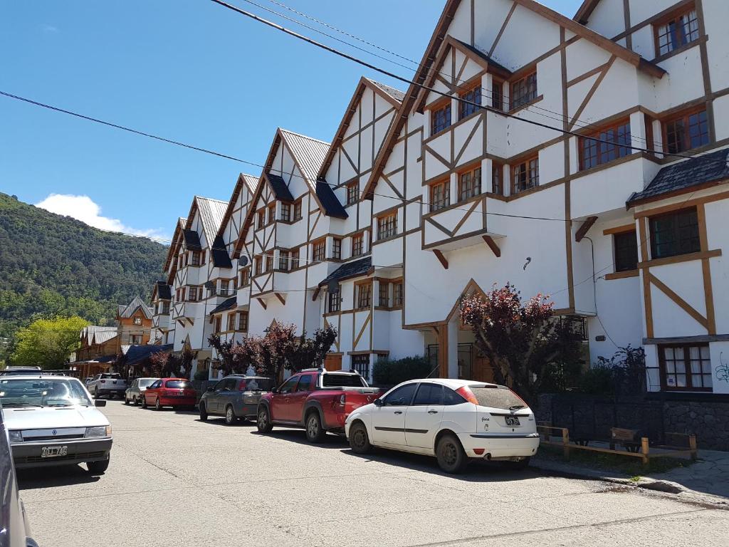 una calle con coches estacionados frente a un edificio en Coronel Rodhe - Andarlibre en San Martín de los Andes