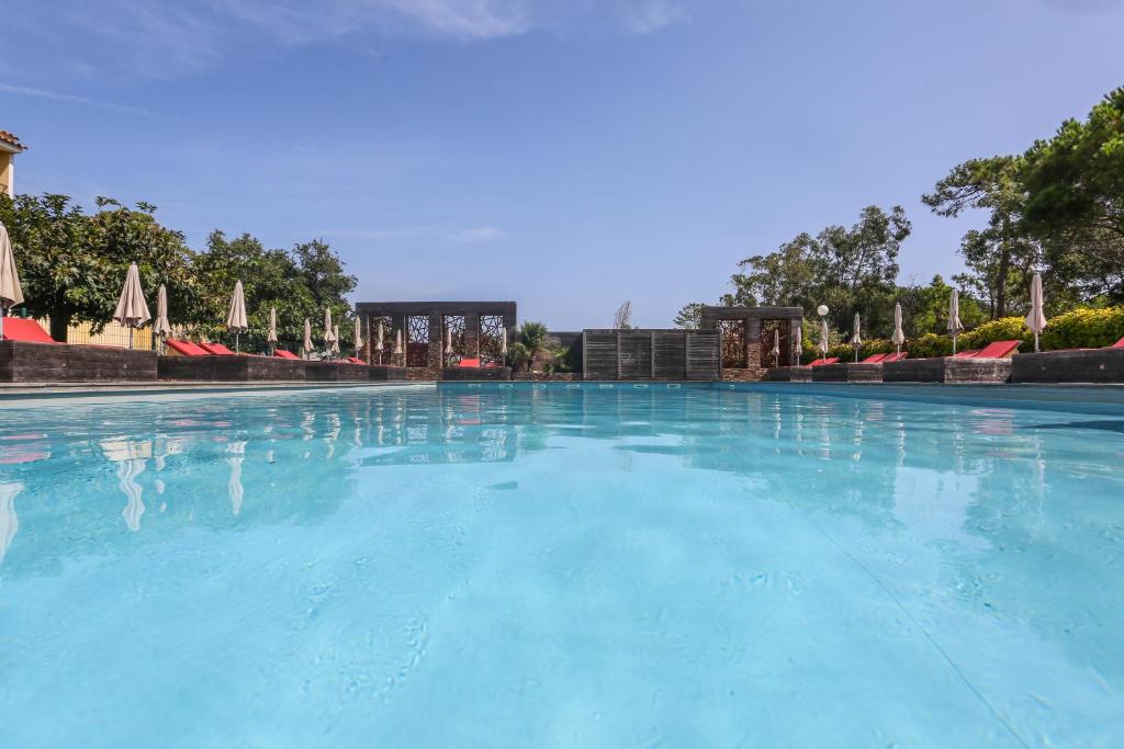 une grande piscine avec de l'eau bleue et des parasols dans l'établissement Isola Hôtel, à Borgo