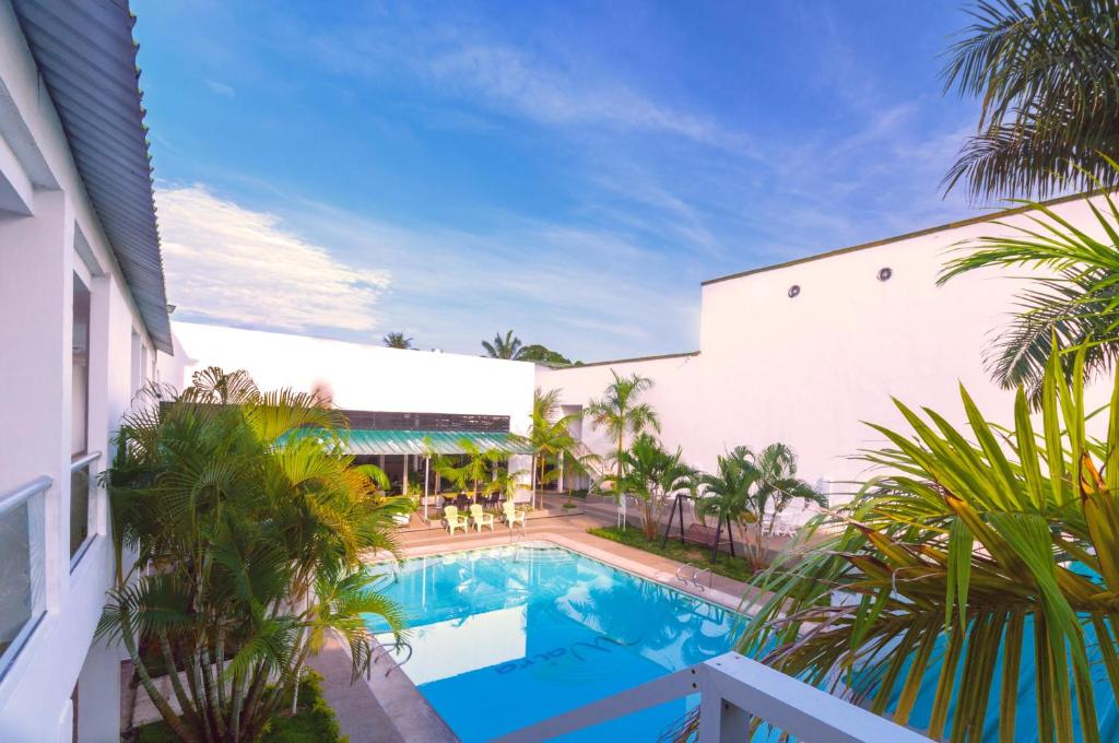 a swimming pool next to a building with palm trees at Waira Suites in Leticia