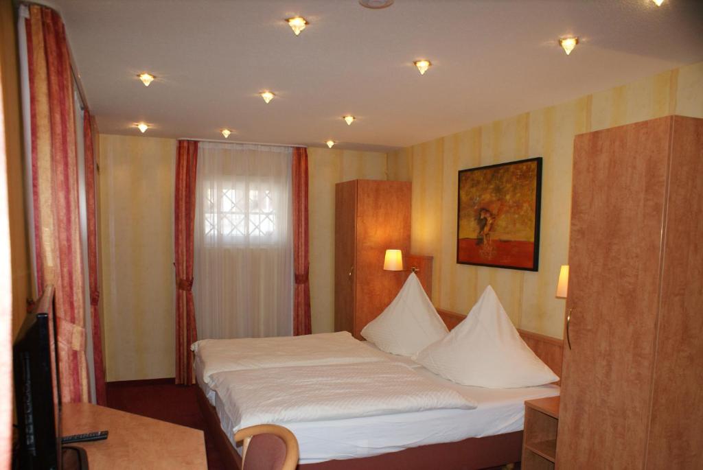 a hotel room with a bed with white sheets at Hotel Altes Rathaus in Ostfildern