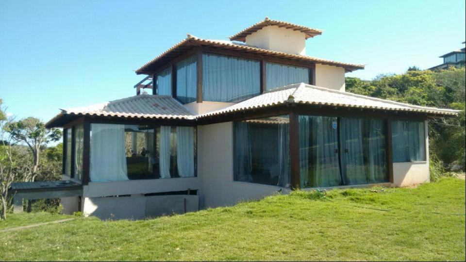 una casa con grandes ventanas de cristal en una colina en Villa Ferradura, en Búzios