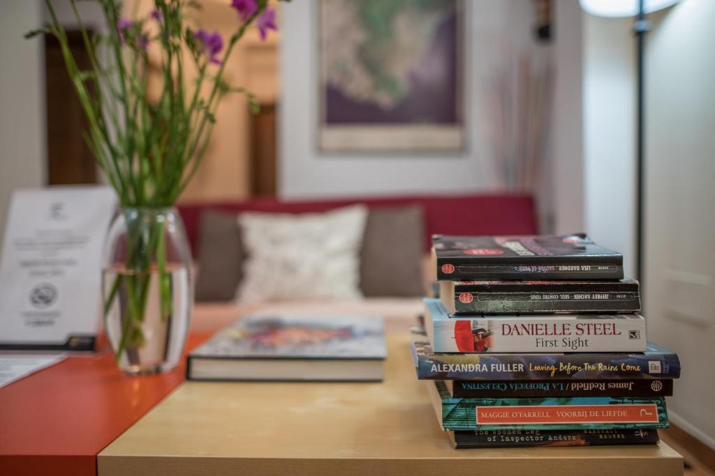 uma pilha de livros sentados numa mesa com um vaso em Hotel Morales em Ronda