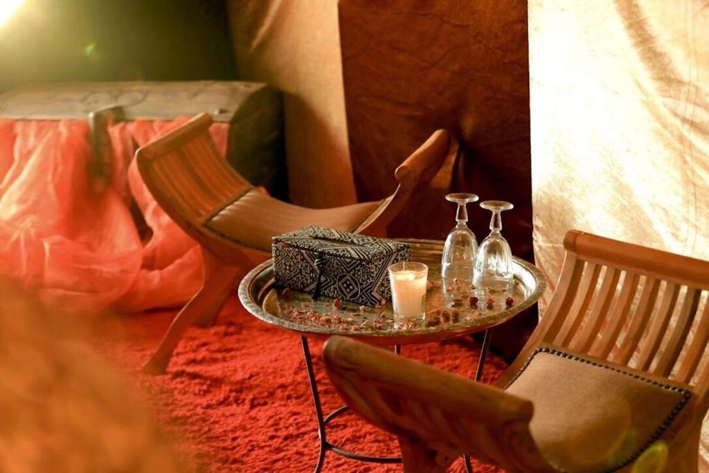 un tavolo con due sedie e due bicchieri e candele di Bivouac de Luxe Le Pacha a M'Hamid