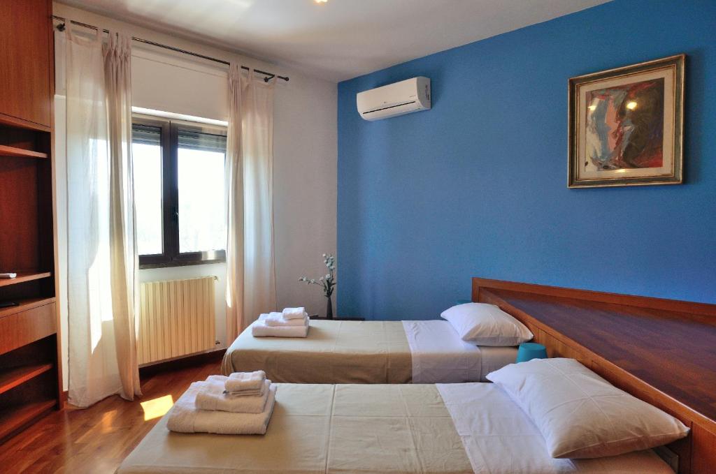 a bedroom with two beds and a blue wall at Bed and Breakfast La Villa AMBIENTI SANIFICATI CON GENERATORE DI OZONO in Bari