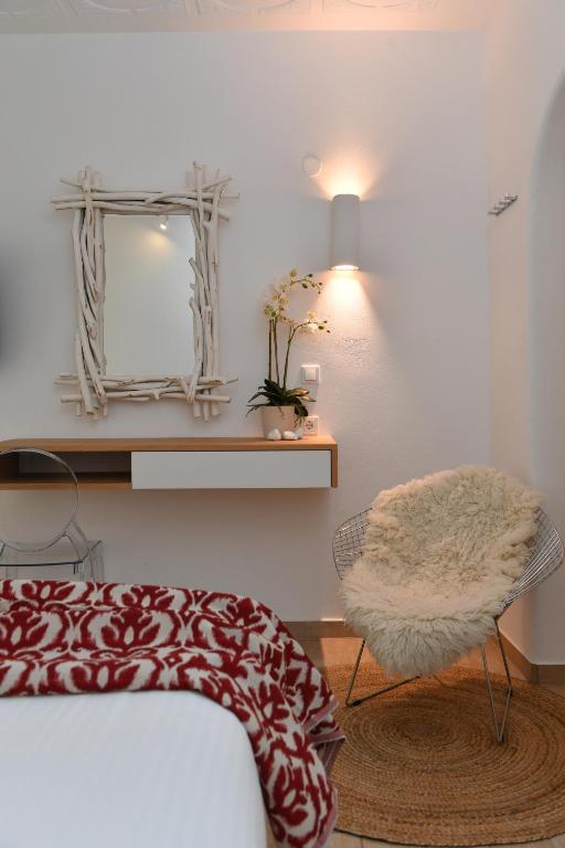 a bedroom with a bed and a mirror and a chair at Apollon Boutique Hotel in Parikia