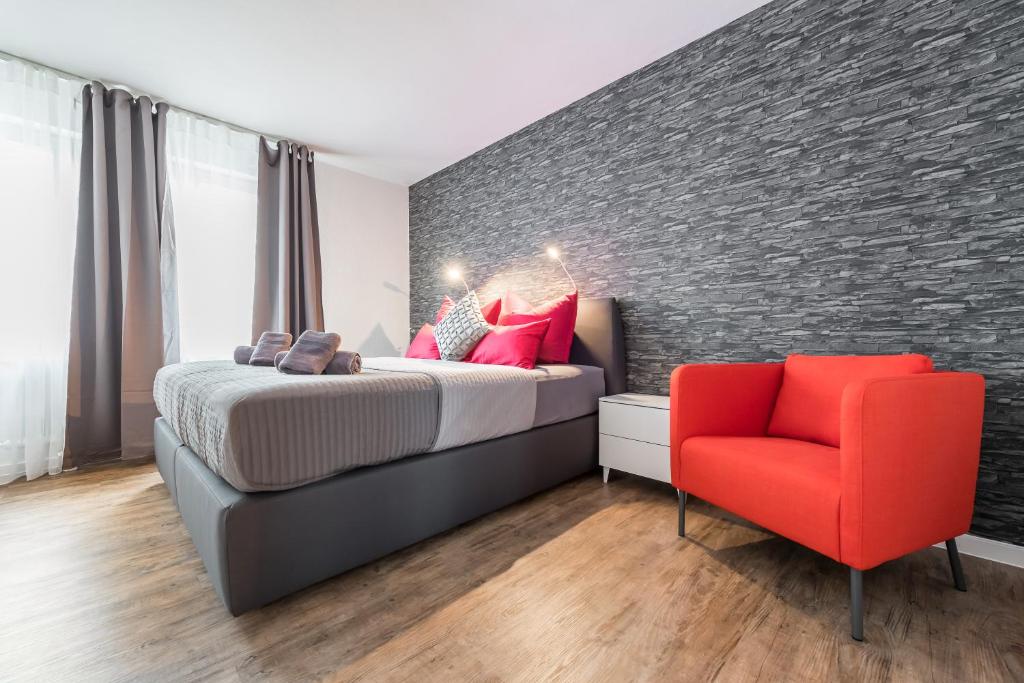 1 dormitorio con 1 cama y 1 silla roja en Wohnen auf Zeit - Innenstadt-Appartements en Freiburg im Breisgau