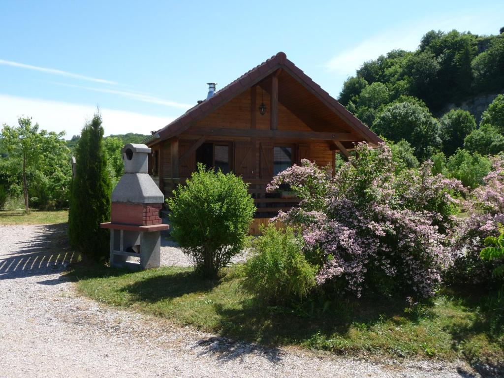 ein kleines Holzhaus mit Kamin und einigen Büschen in der Unterkunft Chalets les Silènes in Doucier