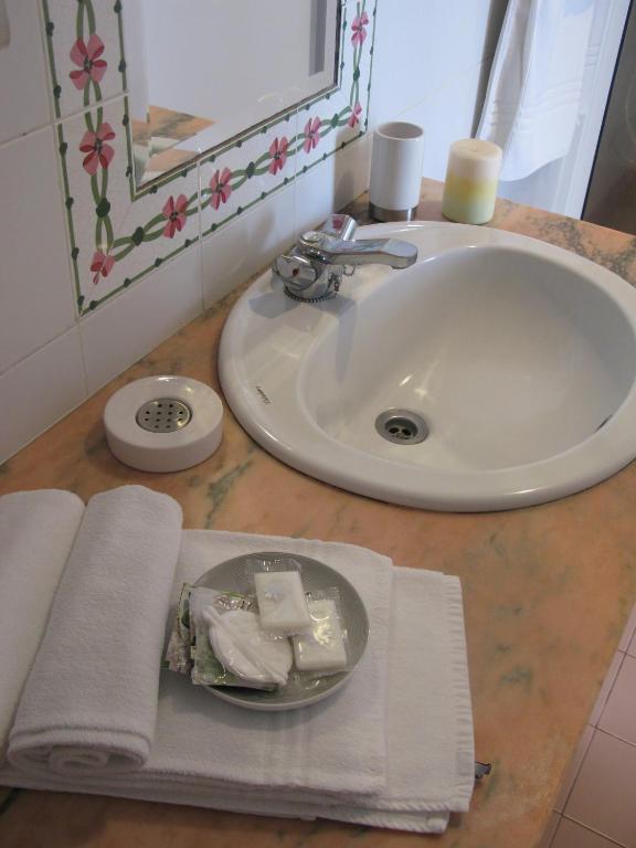a bathroom sink with a plate of soap and towels at Quinta das Buganvílias in Castelo Branco