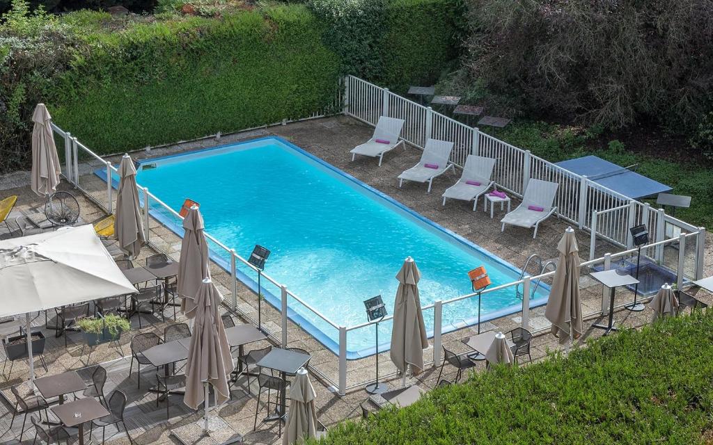 an overhead view of a swimming pool with chairs and umbrellas at Mercure Paris Sud Les Ulis-Courtaboeuf in Les Ulis