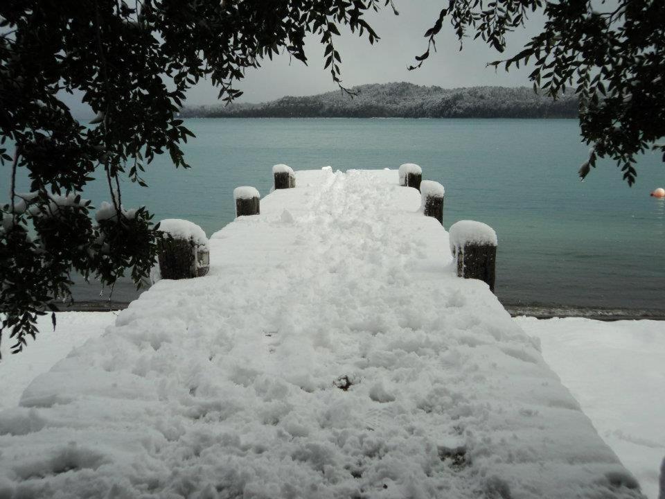 un muelle cubierto de nieve junto a un cuerpo de agua en La Torre de la Cascada en Villa La Angostura