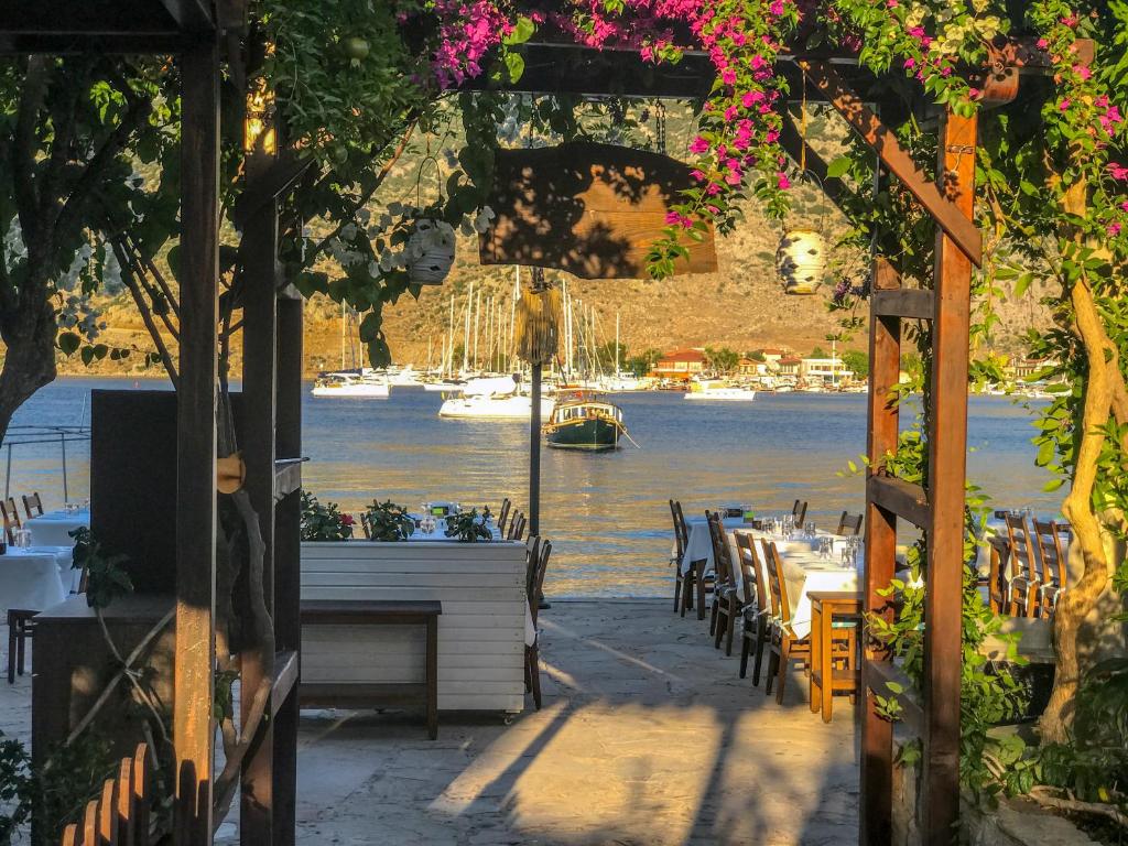 un patio con mesas y sillas y vistas al agua en Giritimu Evleri en Selimiye