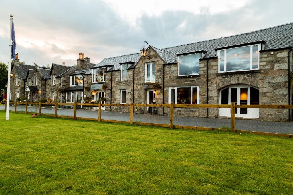 een rij huizen met een groen gazon voor de deur bij The Inn at Loch Tummel in Tummel Bridge