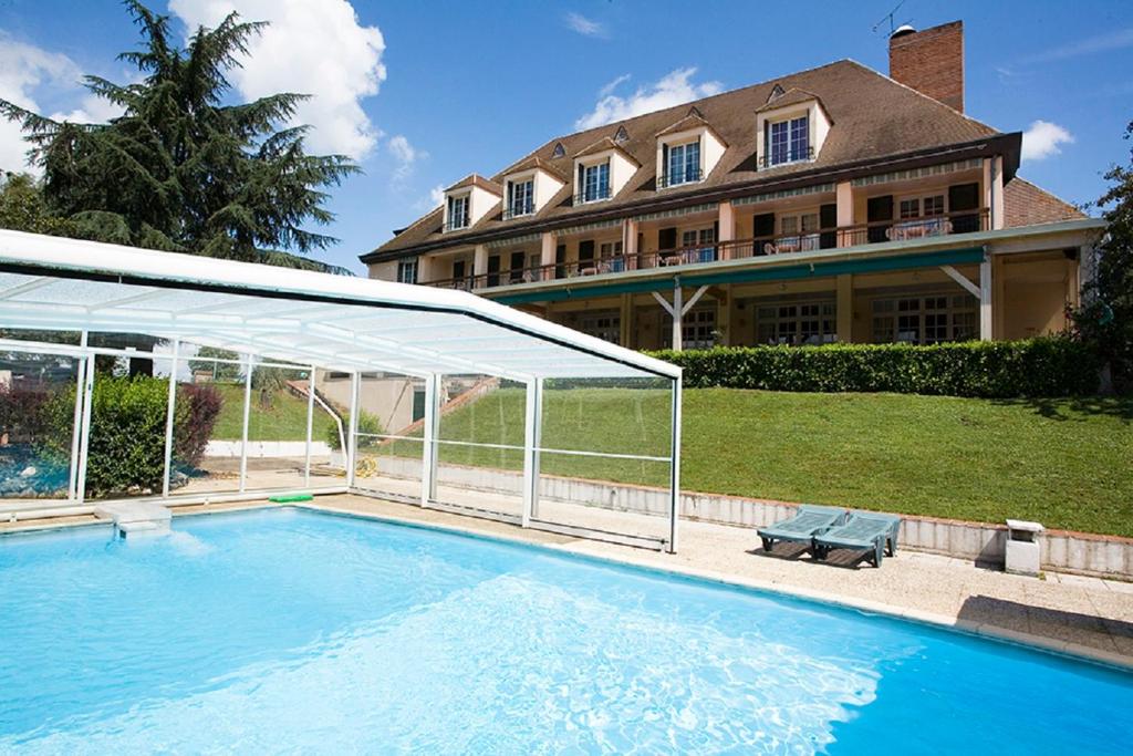 a swimming pool in front of a large house at IRIS HOSTEL et LES BOCAUX D'IRIS in Varennes-sur-Allier