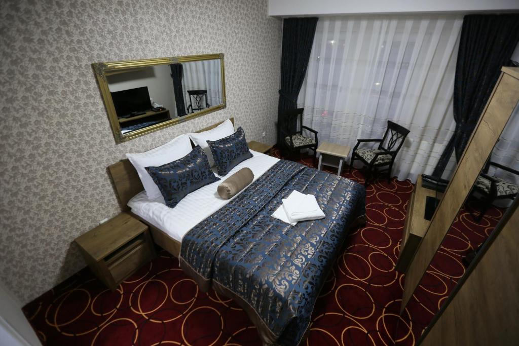 una camera d'albergo con letto e specchio di Hotel Pejton a Pristina