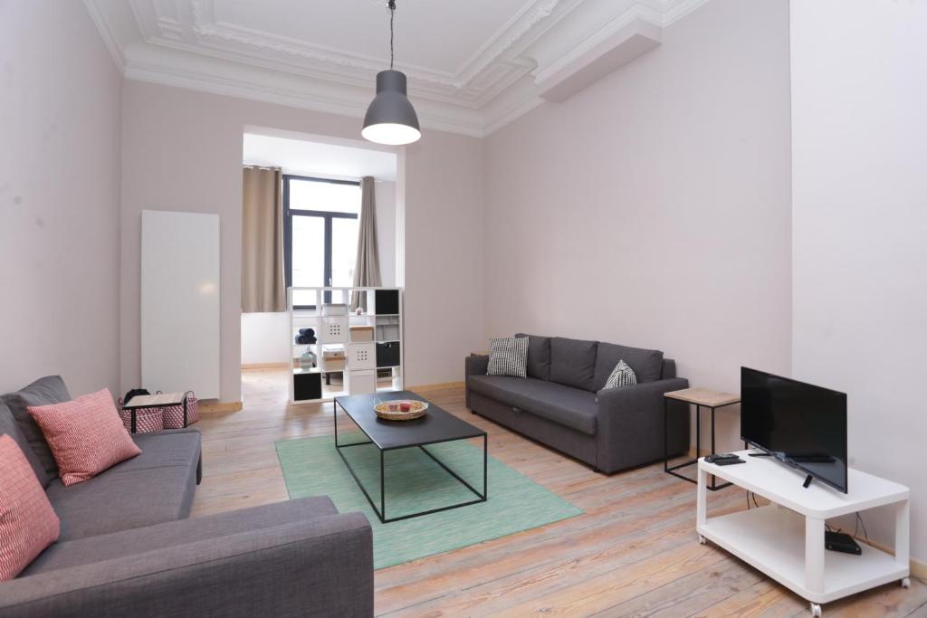 Una sala de estar con un sofá y un televisor. en Parlamentarium apartment, en Bruselas