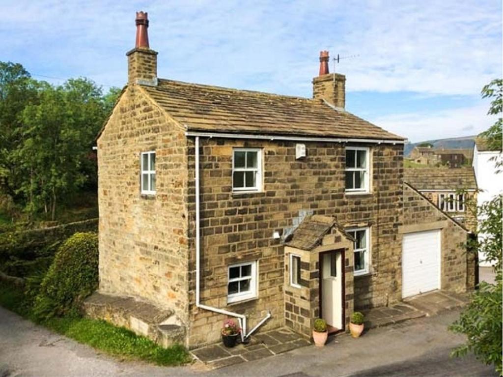 an old brick house with a white garage at Holme House Cottage in Oakworth