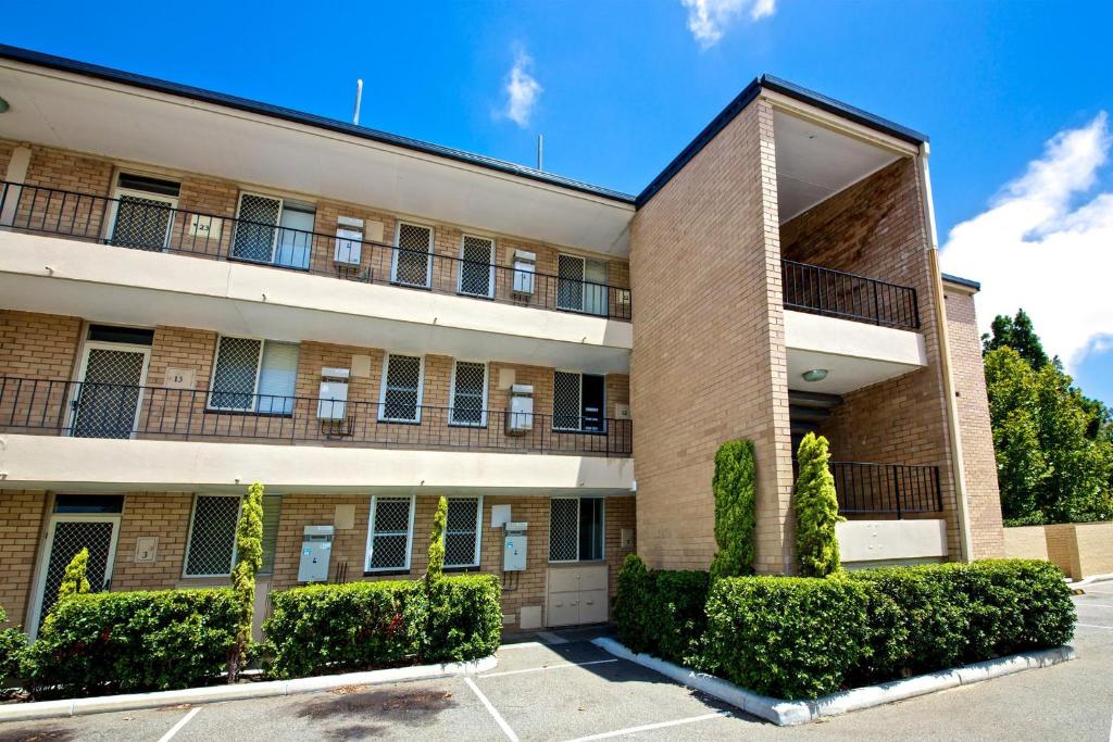 un grand bâtiment avec des buissons devant lui dans l'établissement Pronto Apartments, à Perth