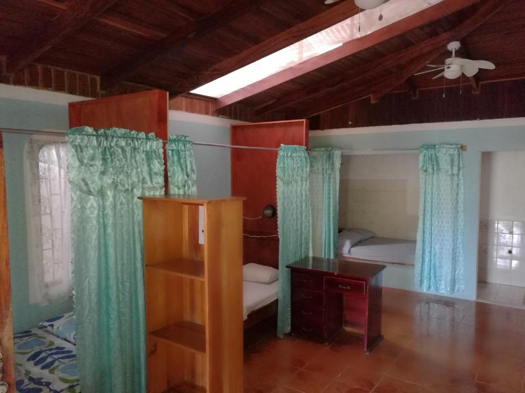 Cet appartement comprend une chambre avec un lit et des rideaux. dans l'établissement Corcovado Wild Hostel, à Puerto Jiménez