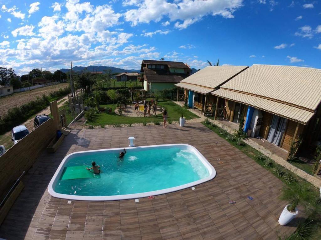 a swimming pool with two people in it next to a house at Noah Rosa Chalés in Praia do Rosa