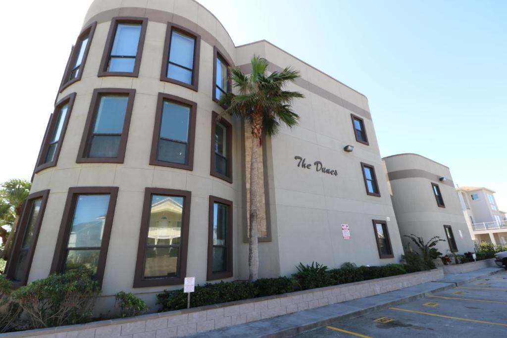 un edificio con una palmera delante de él en The Dunes Condominiums by Cheap Getaway, en South Padre Island