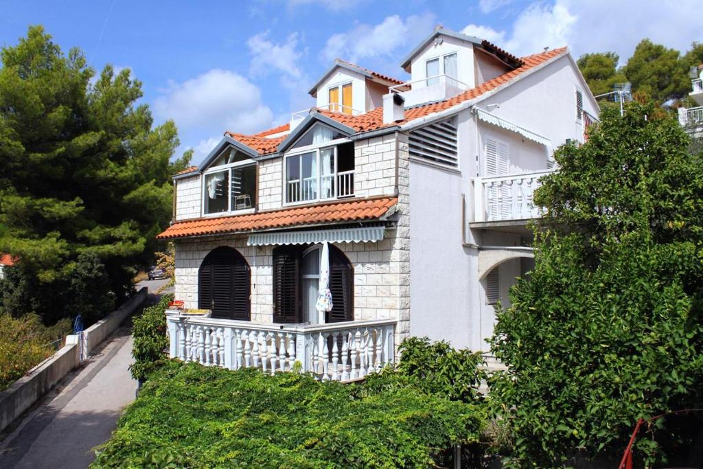 a white house with a balcony on a hill at Apartments by the sea Brna, Korcula - 9149 in Smokvica