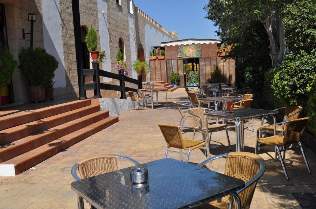un patio con mesas y sillas y un edificio en Apartamentos Rurales Alcazaba de las Torres, en Cañete de las Torres