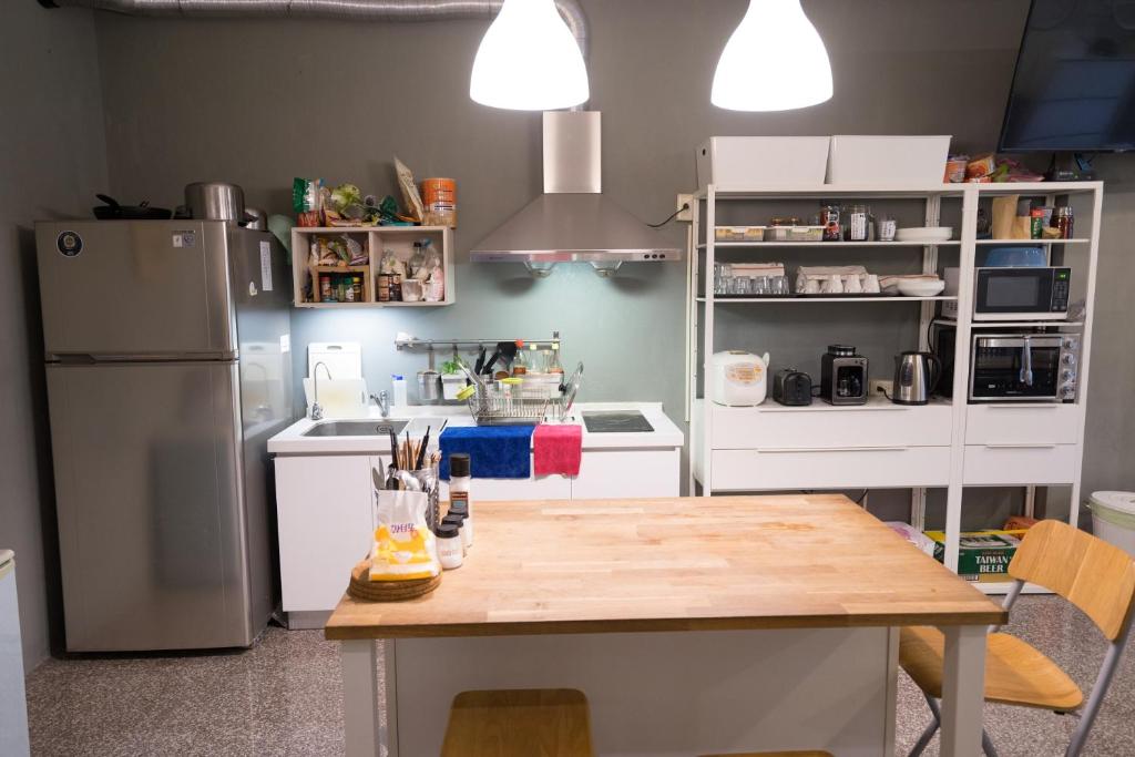 a kitchen with white appliances and a wooden table at Dali Yi International Hostel in Toucheng