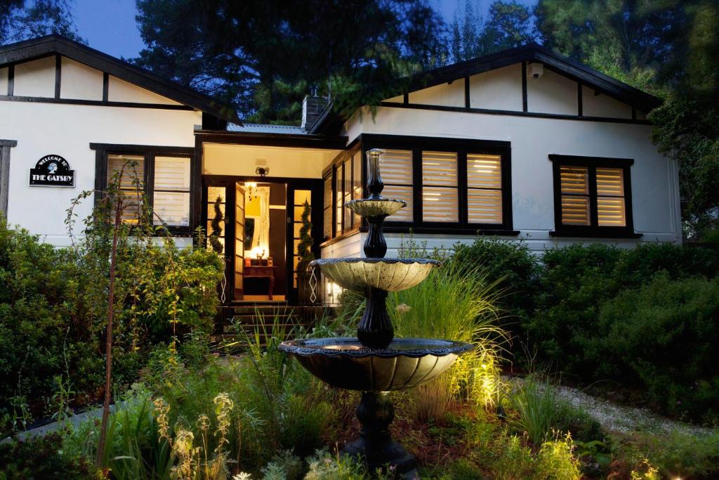 uma casa com uma fonte em frente a uma casa em Mountain Whispers The Gatsby em Katoomba