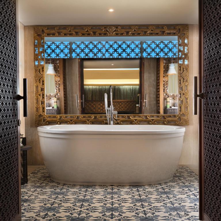 a bathroom with a tub and a large mirror at Anantara Uluwatu Bali Resort in Uluwatu