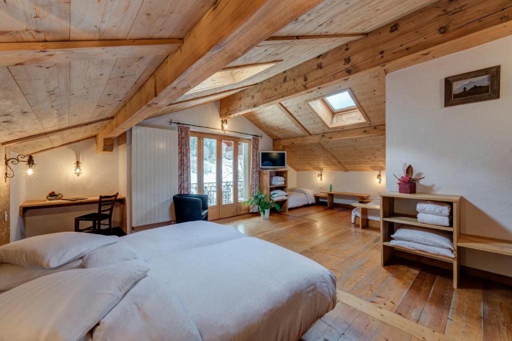 a bedroom with a large bed and a desk at La Vallée Hôtel &Spa in Lourtier