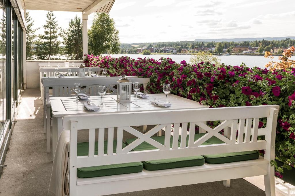 a white table and chairs on a patio with flowers at Tyrifjord Hotell in Vikersund