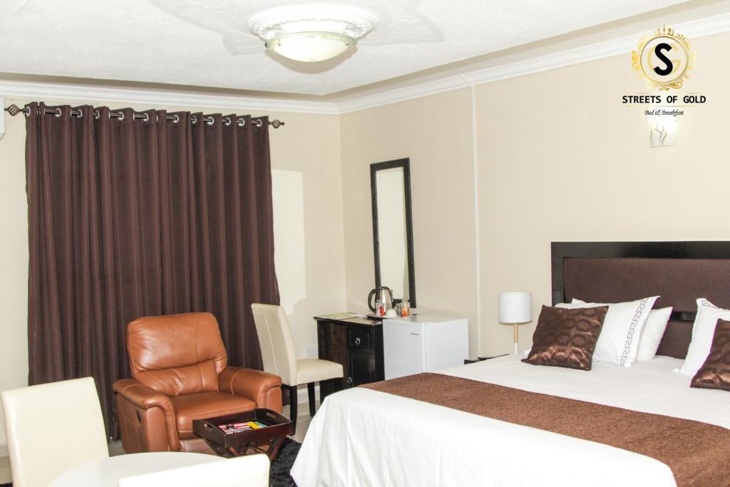 um quarto de hotel com uma cama e uma cadeira em Streets of Gold Guest House em Gaborone