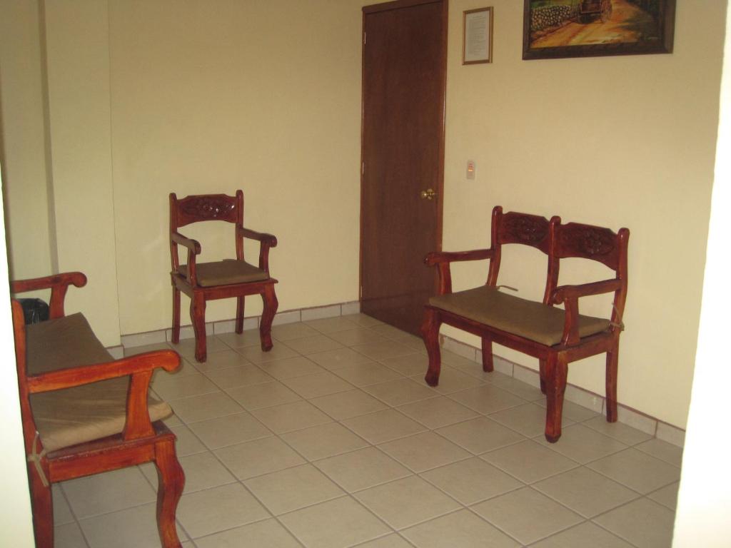 três cadeiras sentadas num piso em azulejo num quarto em Hotel Casa Cortes em Zacatecas