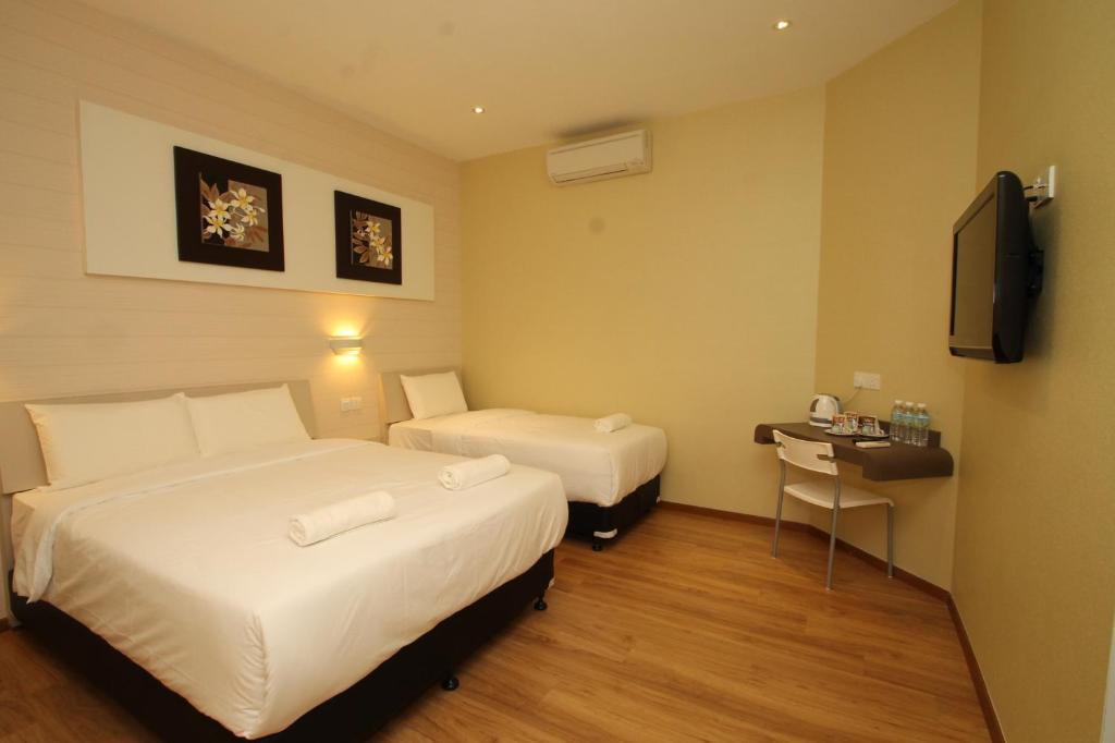 a hotel room with two beds and a television at Ipoh Boutique Hotel in Ipoh